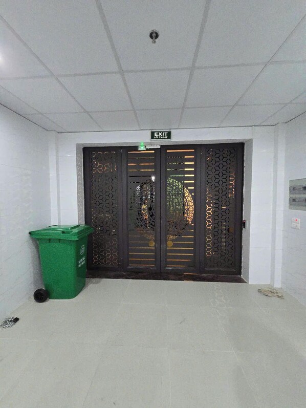 A clean, tiled hallway with a green trash bin and a black door marked "EXIT."