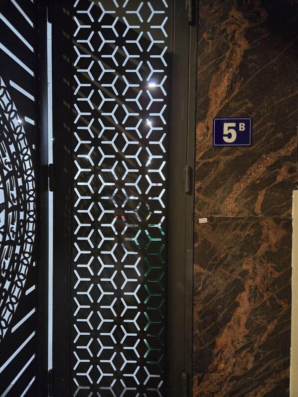 Une porte ornée d’un motif géométrique et portant une plaque indiquant le numéro de la pièce : 5B.