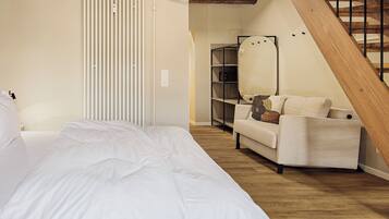 Un dormitorio con cama, sofá, escalera de madera y radiador.