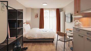 A hotel room with a bed, a desk, a chair, a wardrobe, and a television.