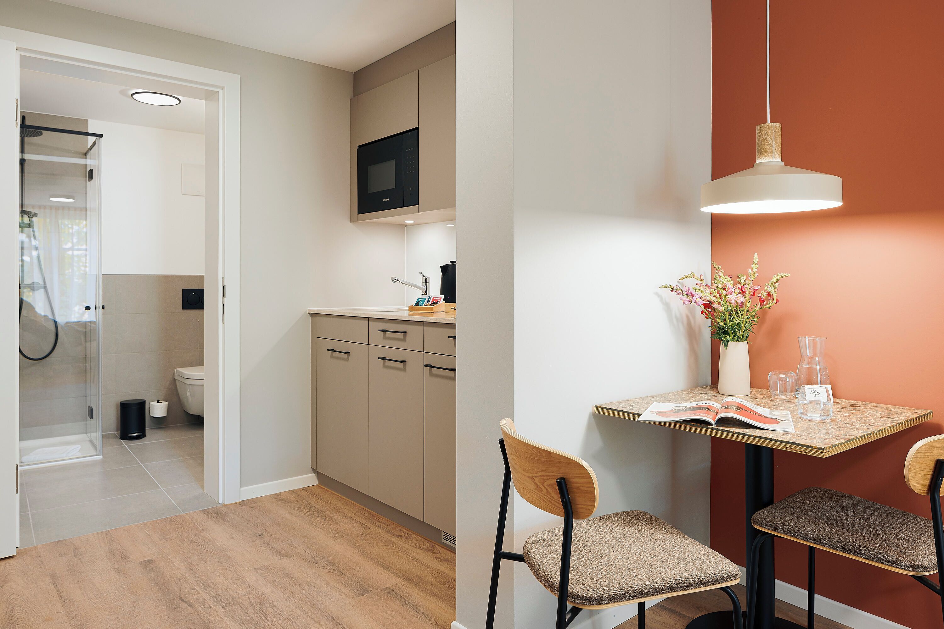 A modern kitchen with a microwave, cabinets, and a dining area with two chairs and a table.