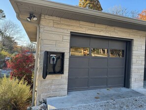A garage with a charging station mounted on the wall. - Stadium Stroll Main Level | Walk to Football | Sleeps 8 · 2 BR · 1 Bath (Bloomington)
