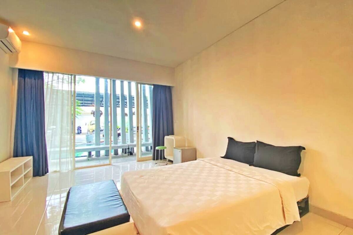 A modern hotel room with a large bed, a small desk, and a balcony with a view.