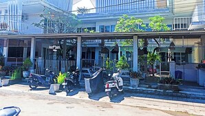 A building with a covered entrance, potted plants, and parked scooters. - Pom Pom's Bali Apartments (Keroboken Kelod)
