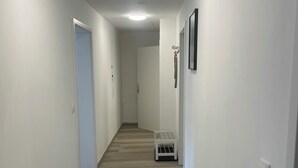 A hallway with a wooden floor, white walls, and a door at the end. - Vacation home Holunder - 7 min. walk to the bathing lake Waldsee Rieden (Rieden)