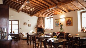 A rustic dining area with wooden tables and chairs, a fireplace, and artwork on the walls.