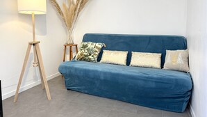 Una habitación con un sofá azul, una lámpara de pie y plumas de pampa decorativas.