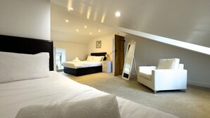 Een slaapkamer met een groot bed, een kleiner bed, een slaapbank en een spiegel.