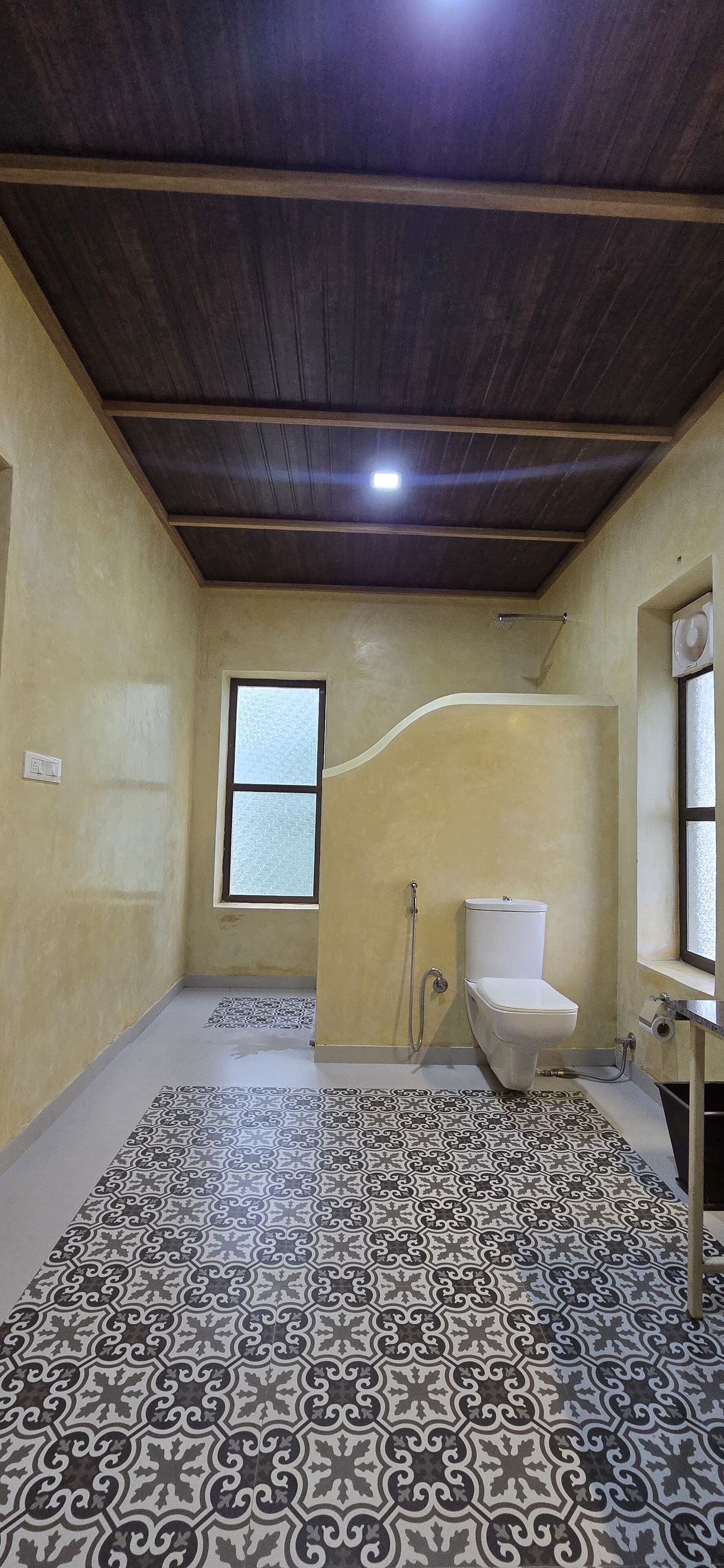 A bathroom with a toilet, shower, and window.
