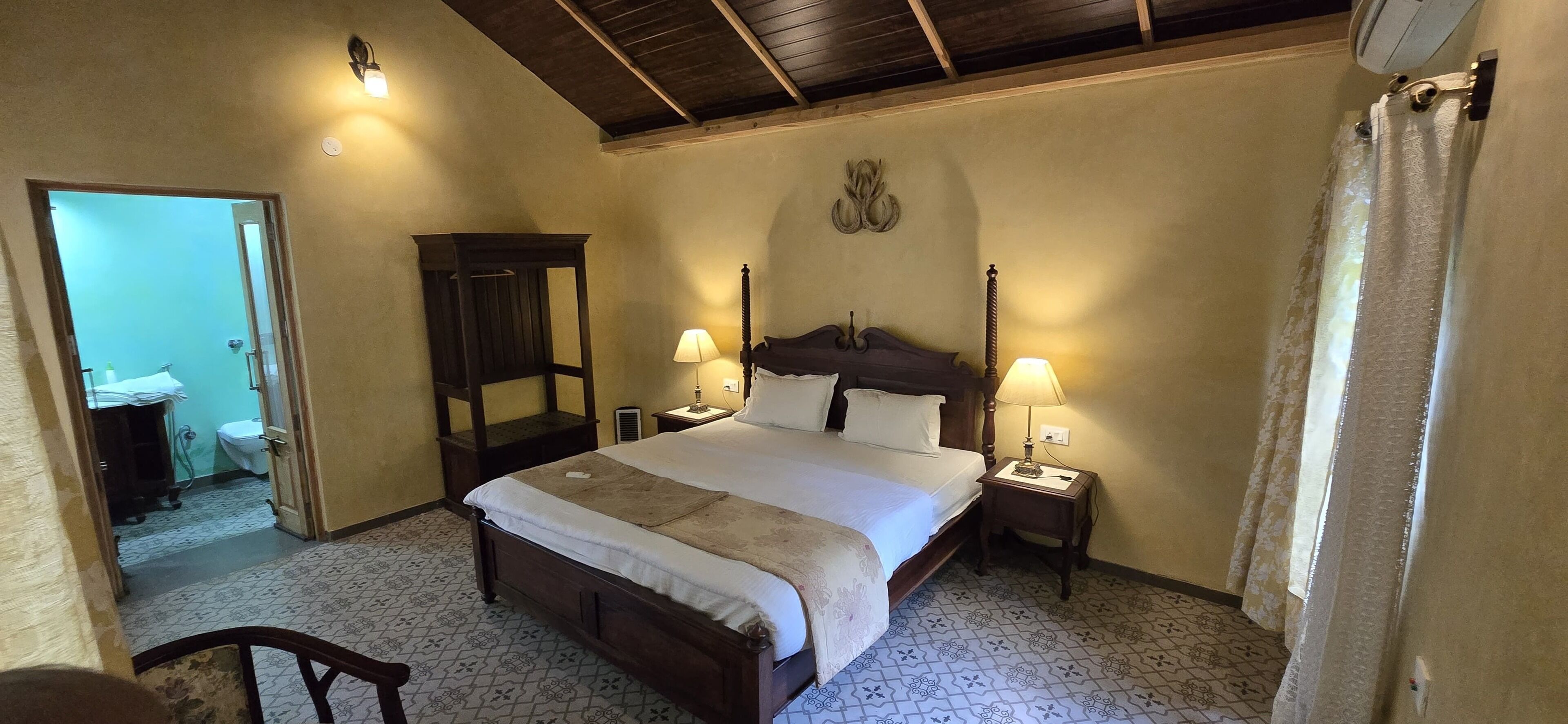 Un dormitorio con una cama grande, dos mesitas de noche con lámparas, un armario de madera y un espejo en la pared.