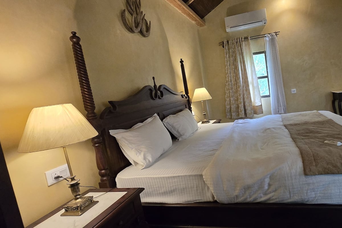 Une chambre d’hôtel avec un grand lit, deux tables de chevet avec des lampes, une chaise et une fenêtre avec des rideaux.