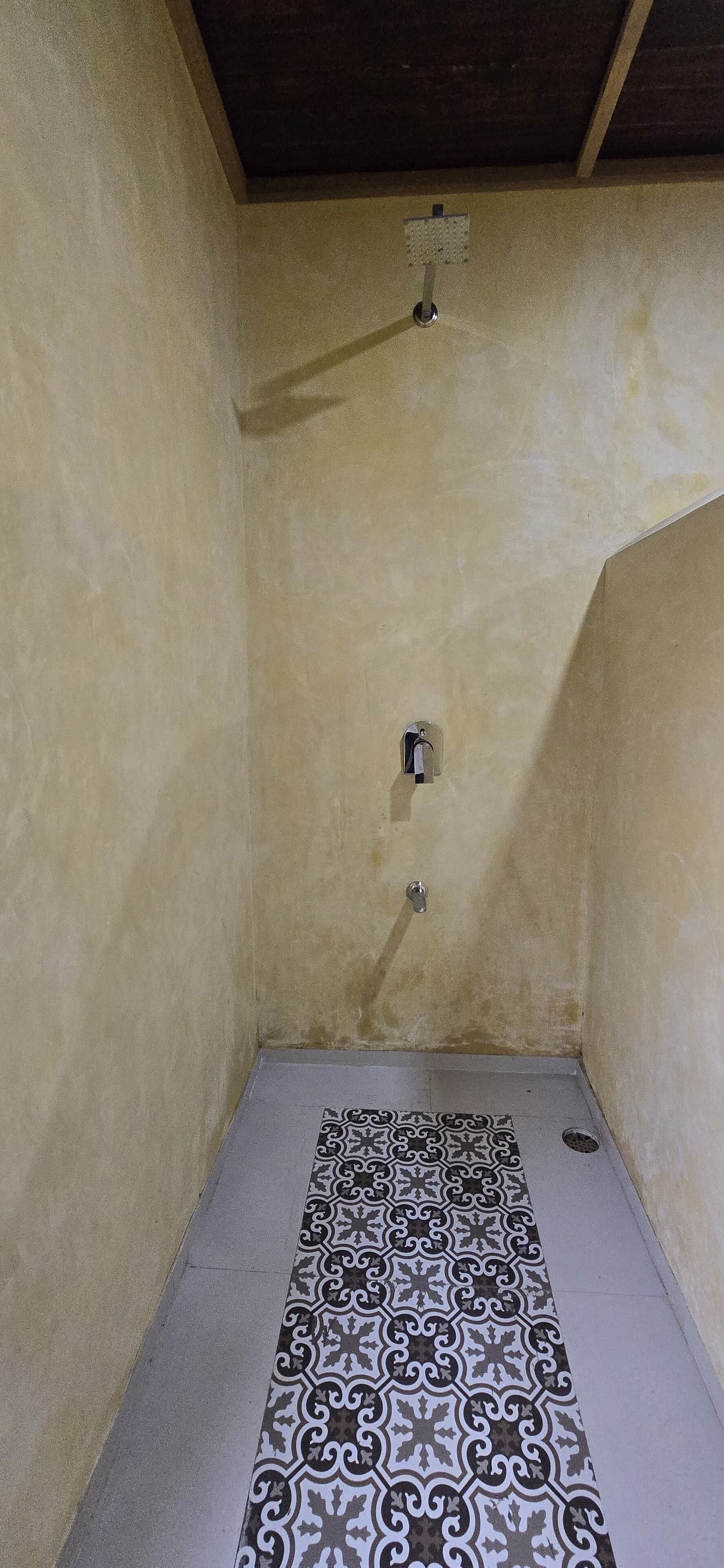 A small, enclosed shower area with a tiled floor and a single faucet.