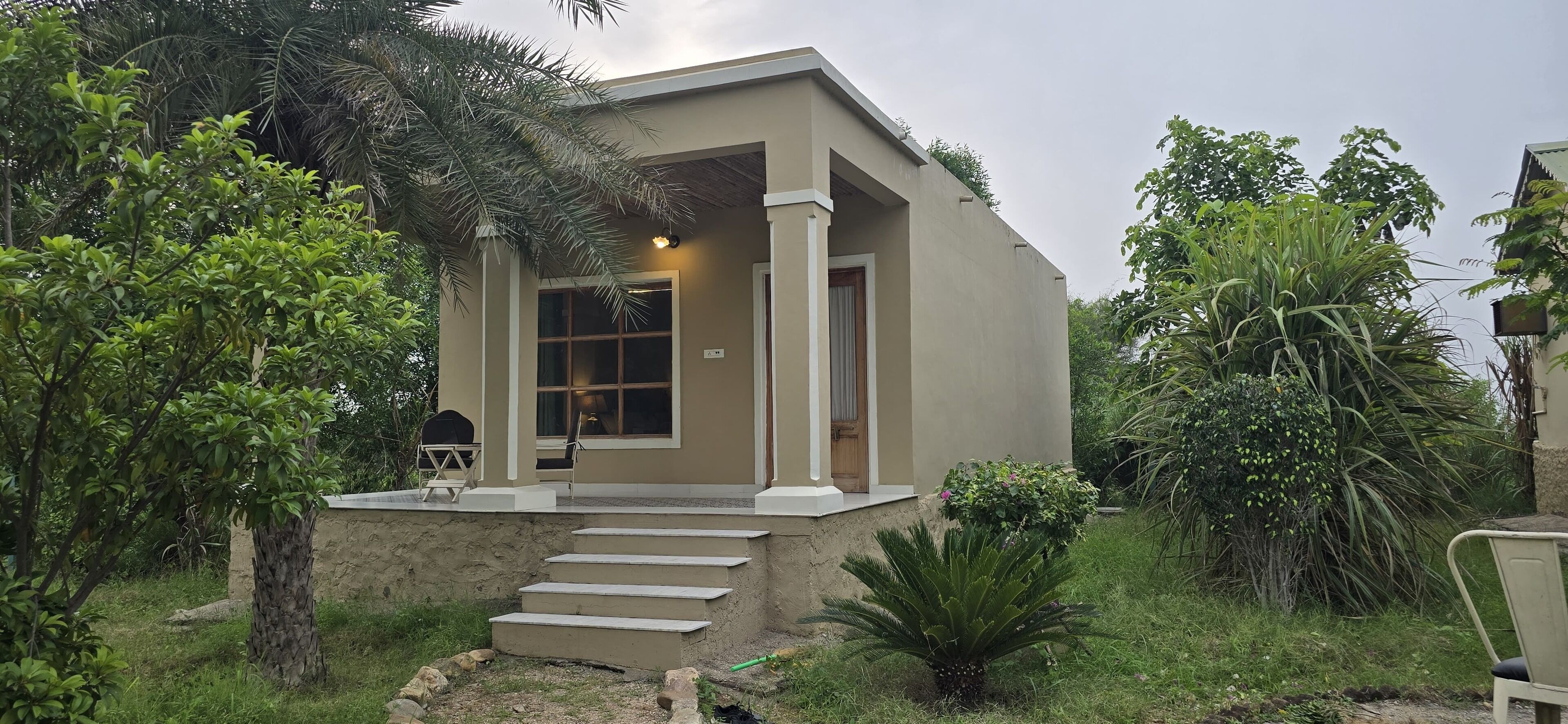 A single-story building with a beige exterior, a front porch with steps, and a door.