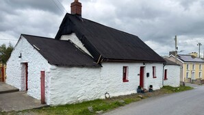 A white building with a black roof and red doors. - Traditional Country Cottage (Pennant)