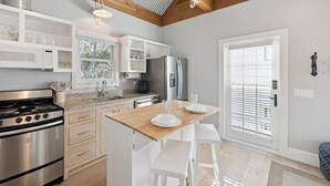 A modern kitchen with a wooden island, stainless steel appliances, and white cabinetry.