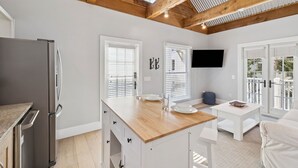 A modern kitchen with a wooden ceiling, white cabinetry, and a built-in refrigerator.