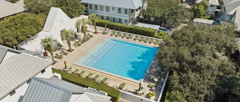 An aerial view of a residential area with a large swimming pool surrounded by lush greenery and modern houses.