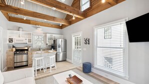 A modern kitchen with white cabinetry, stainless steel appliances, and a wooden ceiling.
