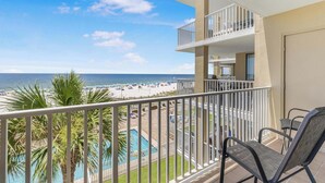 Un balcon avec vue sur une plage et une piscine.