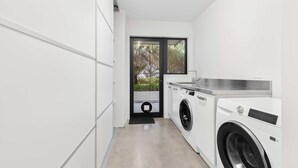 A modern laundry room with a washing machine, dryer, and a large window providing natural light. - All Black # 10 (Hamilton)
