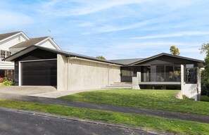 A modern two-story house with a garage, a covered porch, and a well-maintained lawn. - All Black # 10 | Luxury 5-bedroom, Sleeps 10 (Hamilton)