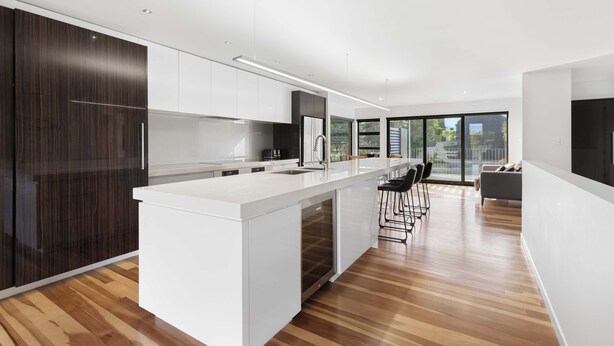 A modern kitchen with a central island, white cabinetry, and a large window providing natural light. - All Black # 10 (Hamilton)