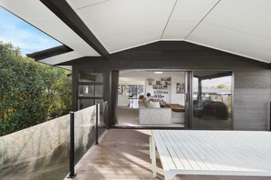 A modern house with a balcony, a dining area, and a living room with a sofa and a coffee table. - All Black # 10 | Luxury 5-bedroom, Sleeps 10 (Hamilton)