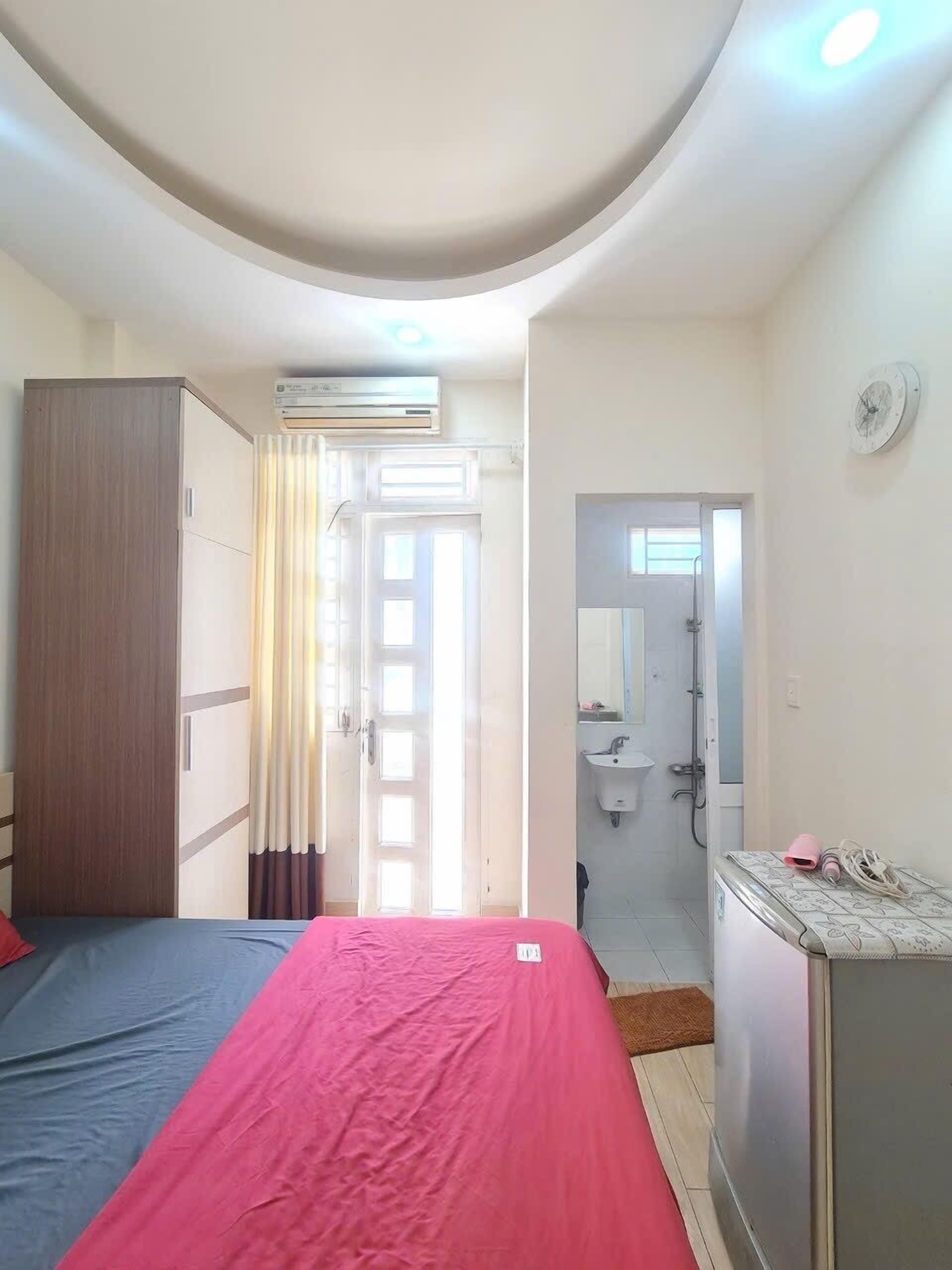 Une chambre comprenant un lit, une armoire, un appareil de climatisation, une salle de bain avec un lavabo et une douche.