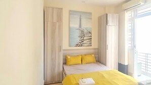 Una camera da letto con un letto, un quadro raffigurante un faro e una finestra con tende.