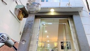 Un edificio moderno con ingresso in vetro, uno scooter parcheggiato all'esterno e cavi elettrici a vista.