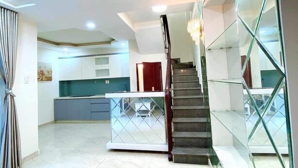 Un'ampia zona giorno con cucina moderna, una scala con ringhiere in vetro e un'ampia finestra che offre luce naturale.