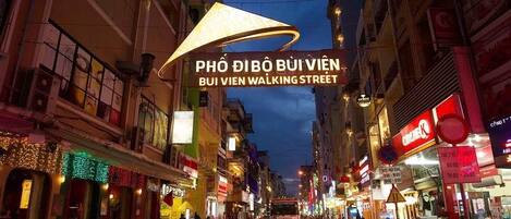 Escena de calle concurrida con un letrero iluminado que dice "PHÒ DIBÒ BUI VIÊN BUI VIÊN WALKING STREET".