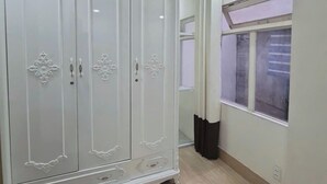 Un'ampia stanza con un grande armadio bianco, una finestra con tende e un soffitto con faretti.