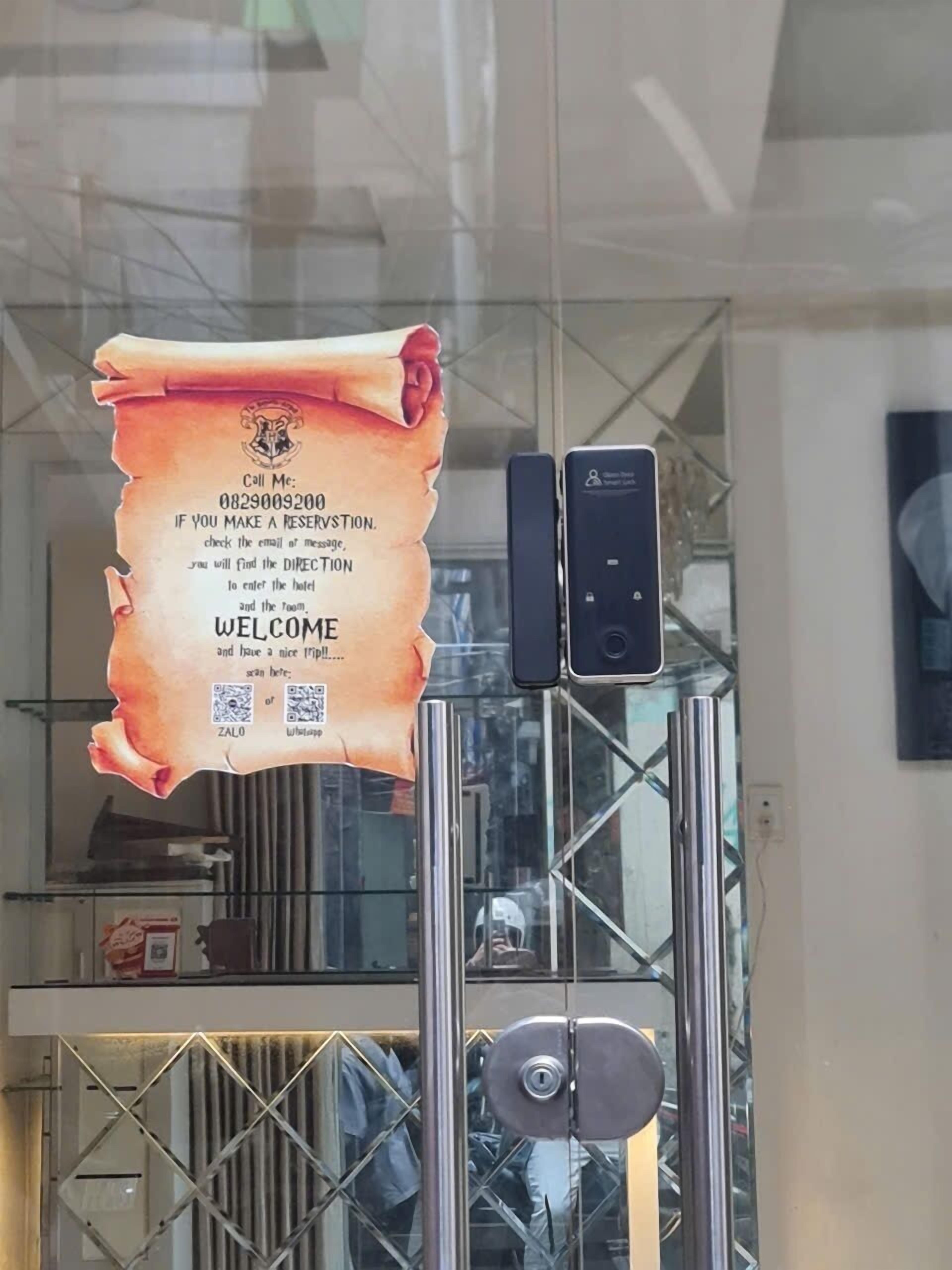 Una puerta de cristal con un letrero de bienvenida, un teclado numérico y un código QR.