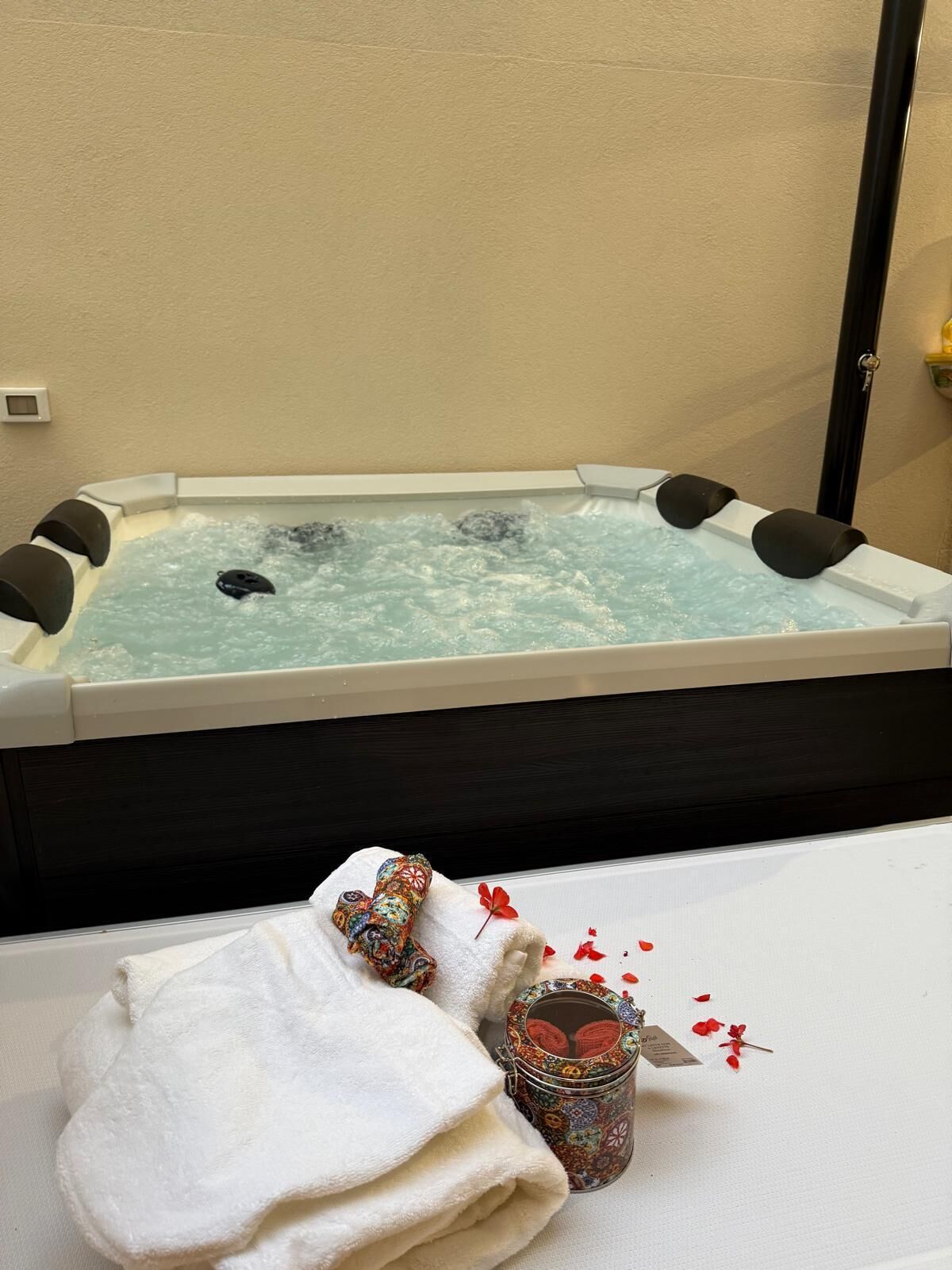A hot tub with a white towel and a decorative jar on a white table.