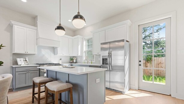 A modern kitchen with white cabinets, a large island with stools, stainless steel appliances, and pendant lighting. - New River Oaks •  River Ranch • King • A+ Location • Premier Host • EV Charger (Lafayette)