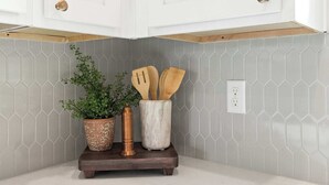 A kitchen with white cabinets, a hexagonal tile backsplash, a wooden countertop, a potted plant, and wooden utensils. - New River Oaks •  River Ranch • King • A+ Location • Premier Host • EV Charger (Lafayette)