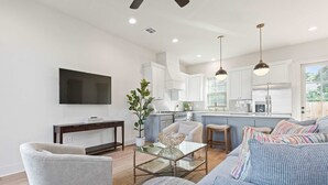 A modern living room with a sofa, a coffee table, and a TV mounted on the wall. - New River Oaks •  River Ranch • King • A+ Location • Premier Host • EV Charger (Lafayette)