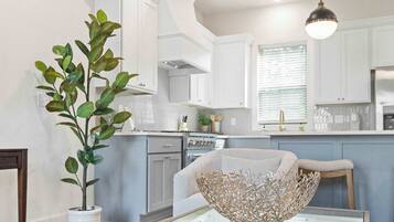Una cocina moderna con armarios blancos, una mesa de comedor de vidrio y una planta en maceta.