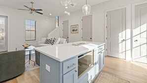 A modern kitchen with a central island, pendant lighting, and a ceiling fan.