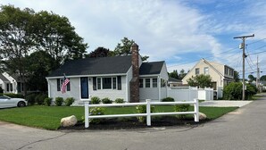 A residential house with a white exterior, a brick chimney, and a small front yard with a white picket fence. -  Charming Cottage w/ WiFi, AC in York, Walking Distance to Long Sands Beach (York)