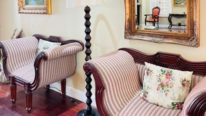 A room with two upholstered chairs, a floor lamp, and a large mirror on the wall. - Presidential Boutique Hotel (Durban North)