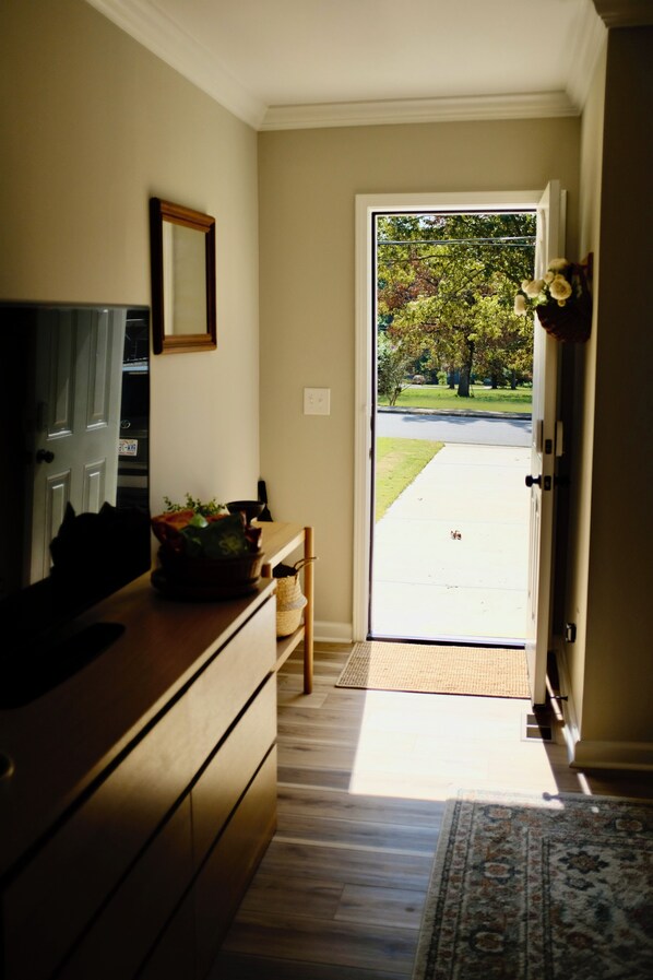 A hallway with a wooden dresser, a mirror, and a door leading outside.