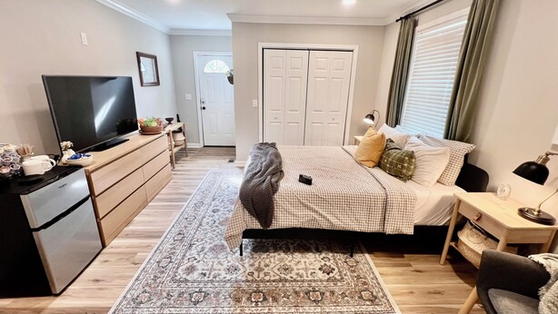 A bedroom with a bed, a desk, a television, and a wardrobe.