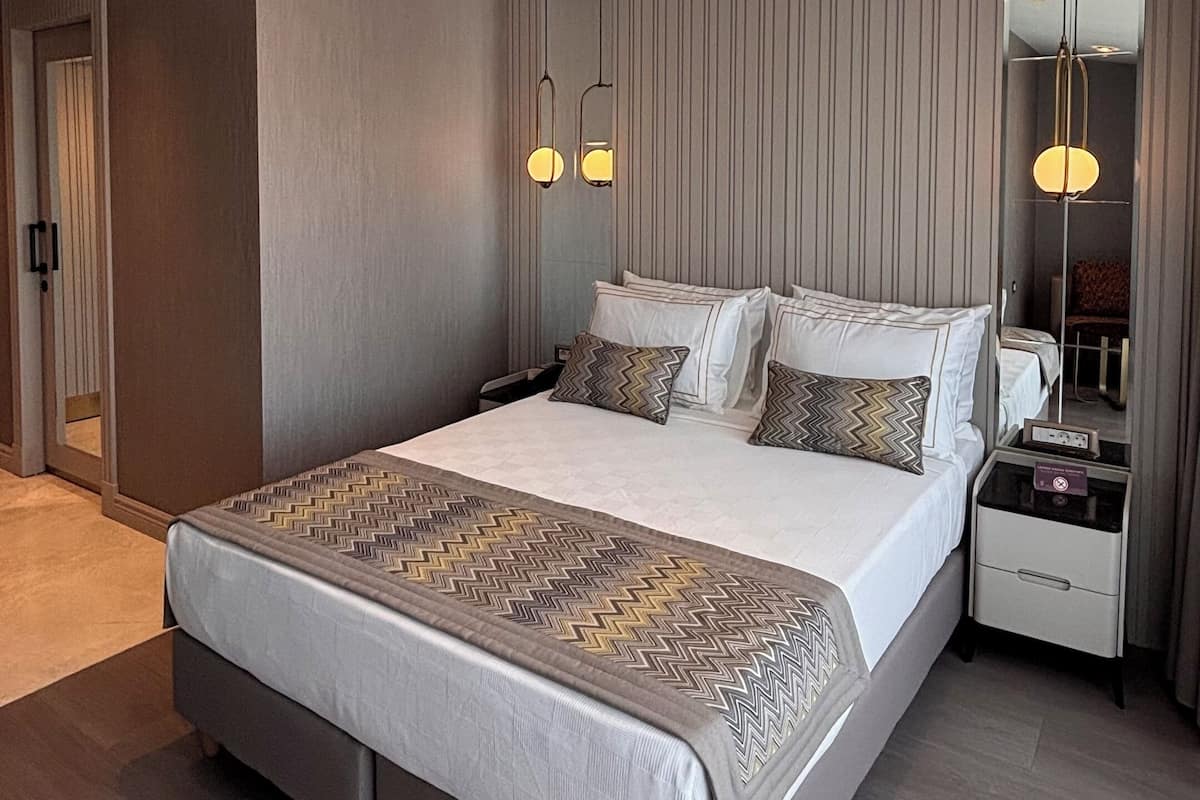 Habitación de hotel moderna con una cama grande, mesitas de noche, un espejo y un armario.