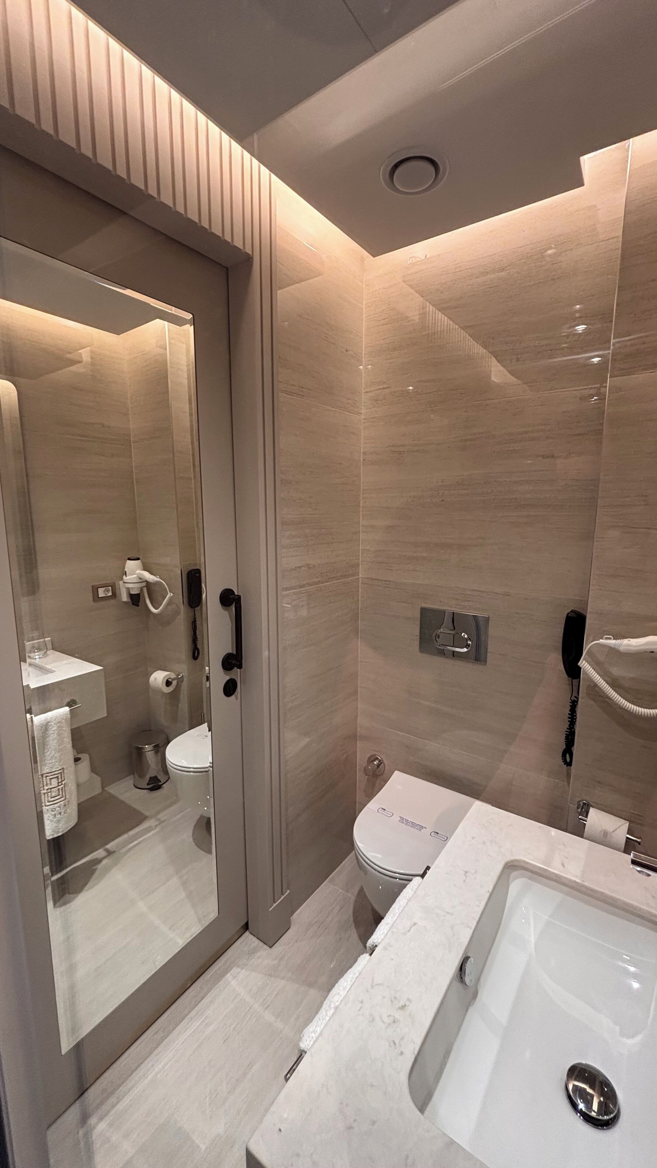 A modern bathroom with a glass shower enclosure, a toilet, and a sink with a mirror.