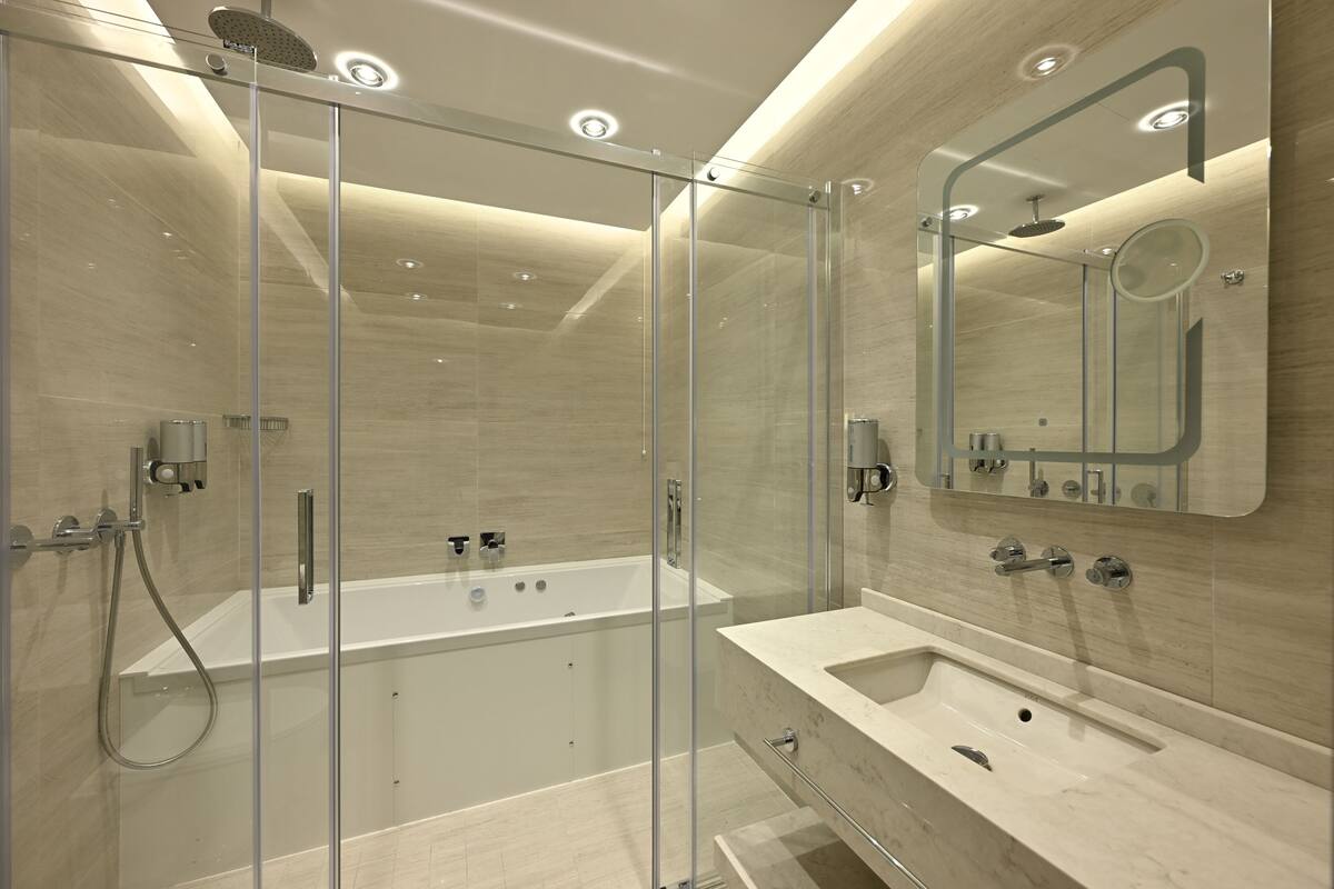 Un baño moderno con ducha envuelta en cristal, una bañera independiente y un tocador con espejo.