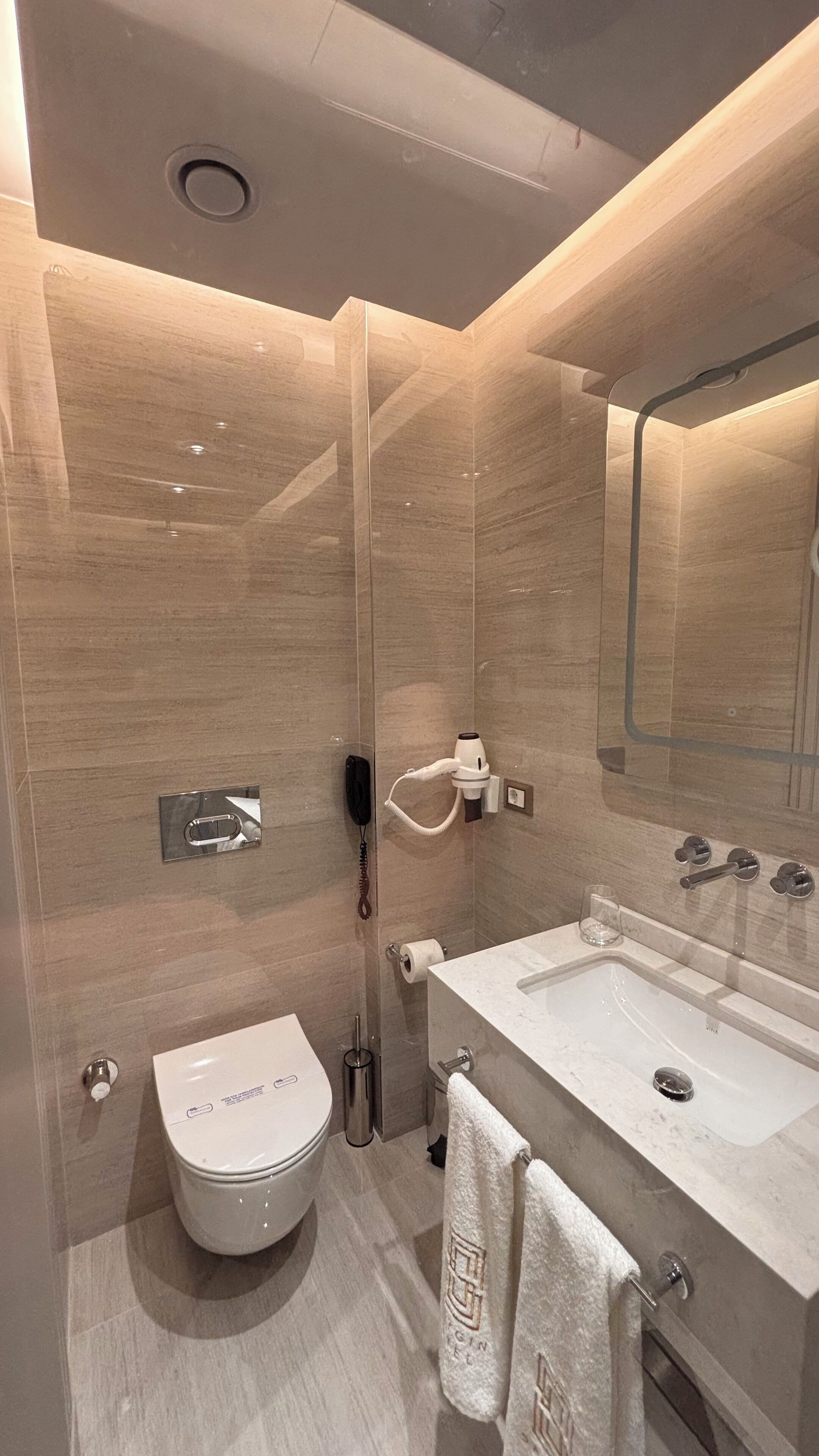 Ein modernes Badezimmer mit Toilette, Bidet und einem großen Waschbecken mit Spiegel.