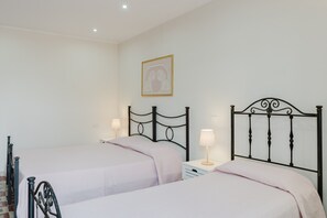 Un dormitorio con dos camas, cada una con una mesita de noche y una lámpara, y un cuadro en la pared.