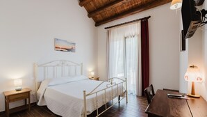 Une chambre à coucher avec un lit, des tables de chevet, un bureau, une lampe et une fenêtre avec des rideaux.
